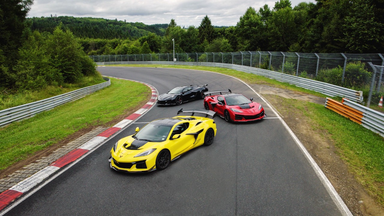 Red, yellow and black Corvettes parked on racetrack.
